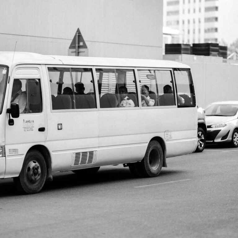 a white bus driving down a street next to tall buildings